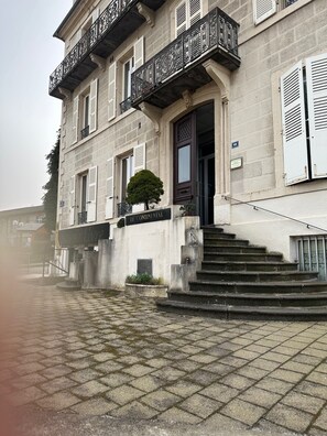 A building with a stone facade, a central entrance with a door, and a staircase leading to the entrance.