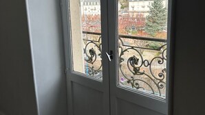 Ein Zimmer mit großem Fenster, einer Tür und einem Balkon mit Metallgeländer.