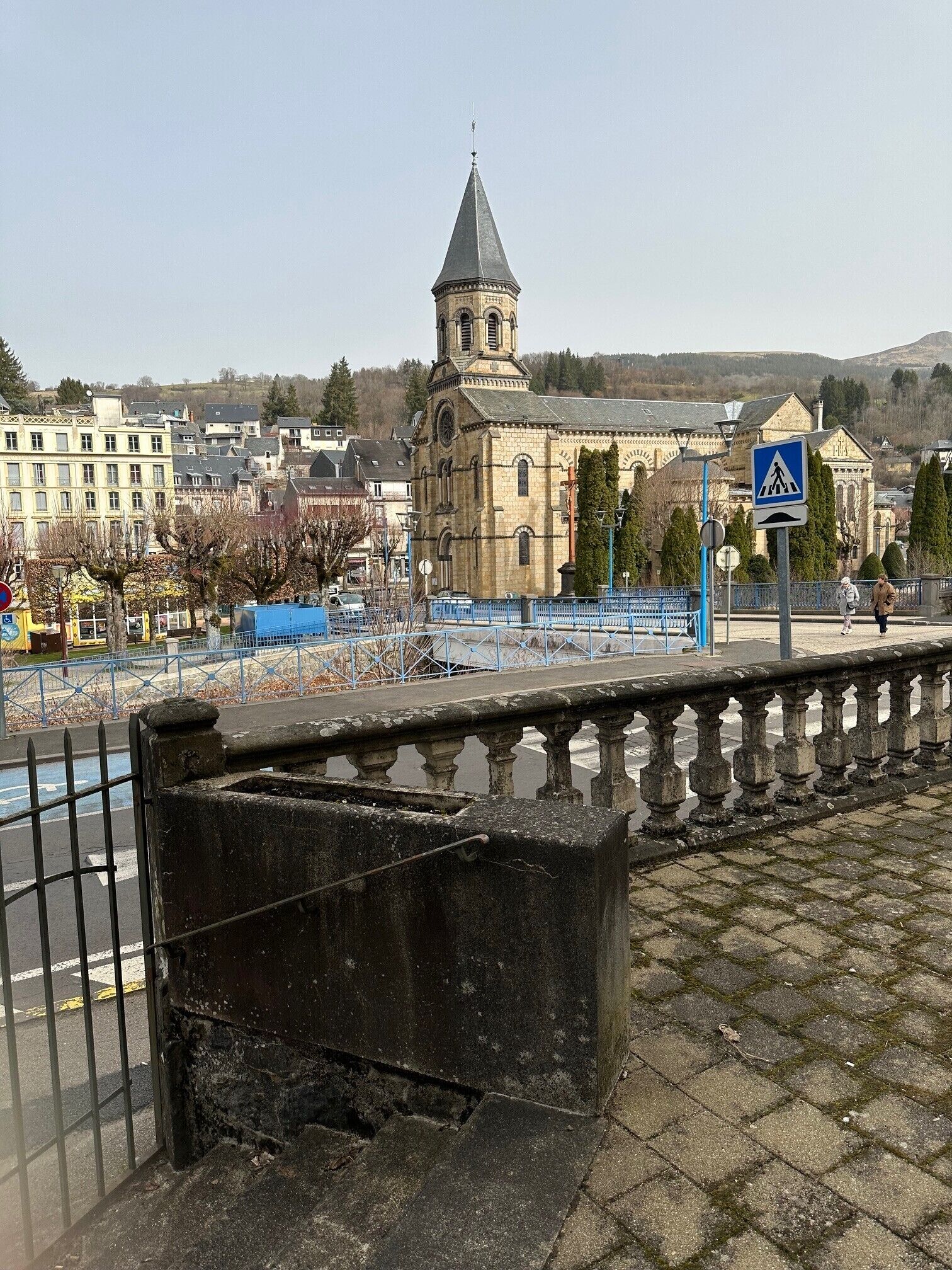 Una iglesia histórica con una torre, una señal de paso para peatones y una cerca azul.