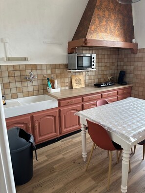 A kitchen with a microwave, sink, and a table with chairs.