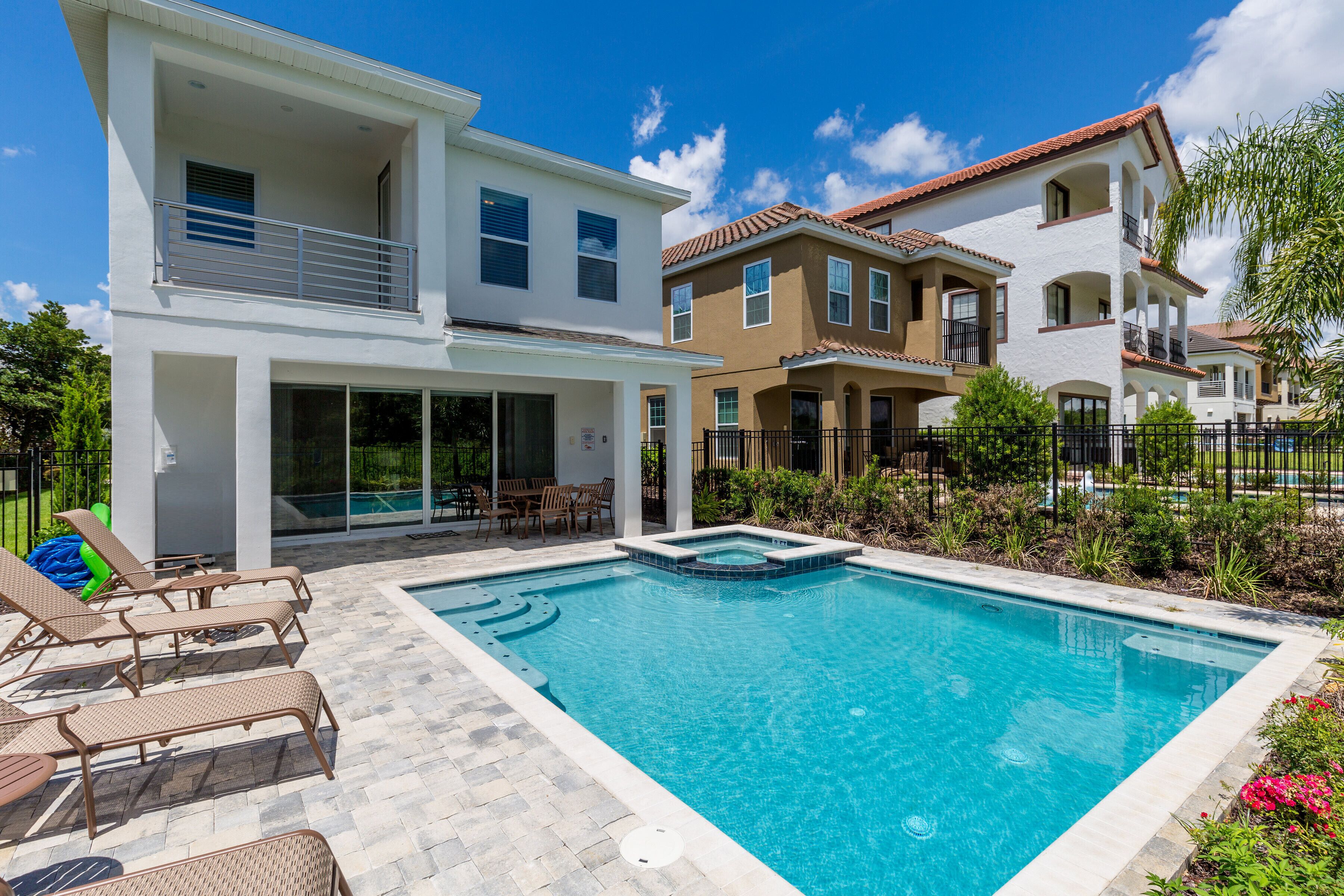 A modern two-story house with a swimming pool, outdoor furniture, and a well-maintained garden.