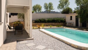 Ein Poolbereich mit Terrasse, Sitzgelegenheiten und Blick auf Bäume und Berge.