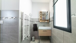 Ein Badezimmer mit weißem Waschbecken, einem Spiegel, einem Handtuchhalter und einer Heizung.