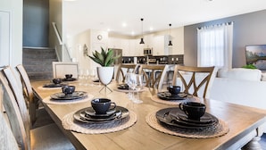 Uma área de jantar com uma mesa de madeira posta para quatro pessoas, rodeada por cadeiras.