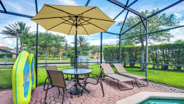 Un patio al aire libre con una mesa, sillas, una sombrilla y una piscina.