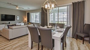 Ein modernes Hotelzimmer mit Essbereich, einer Couch, einem Flachbildfernseher und einem Deckenventilator.