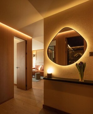 Ein Flur mit einem runden Spiegel, einer Blumenvase und einer Holztür, die zu einem Zimmer führt.
