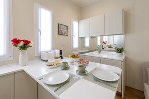 A modern kitchen with white cabinetry, a dining area with a table set for two, and a large mirror above the sink. - Pontaccio, 19 - Your nest in town (Milano)