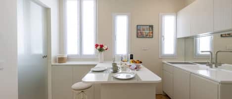 Una cocina moderna con armarios blancos, una isla central y una ventana con vistas.