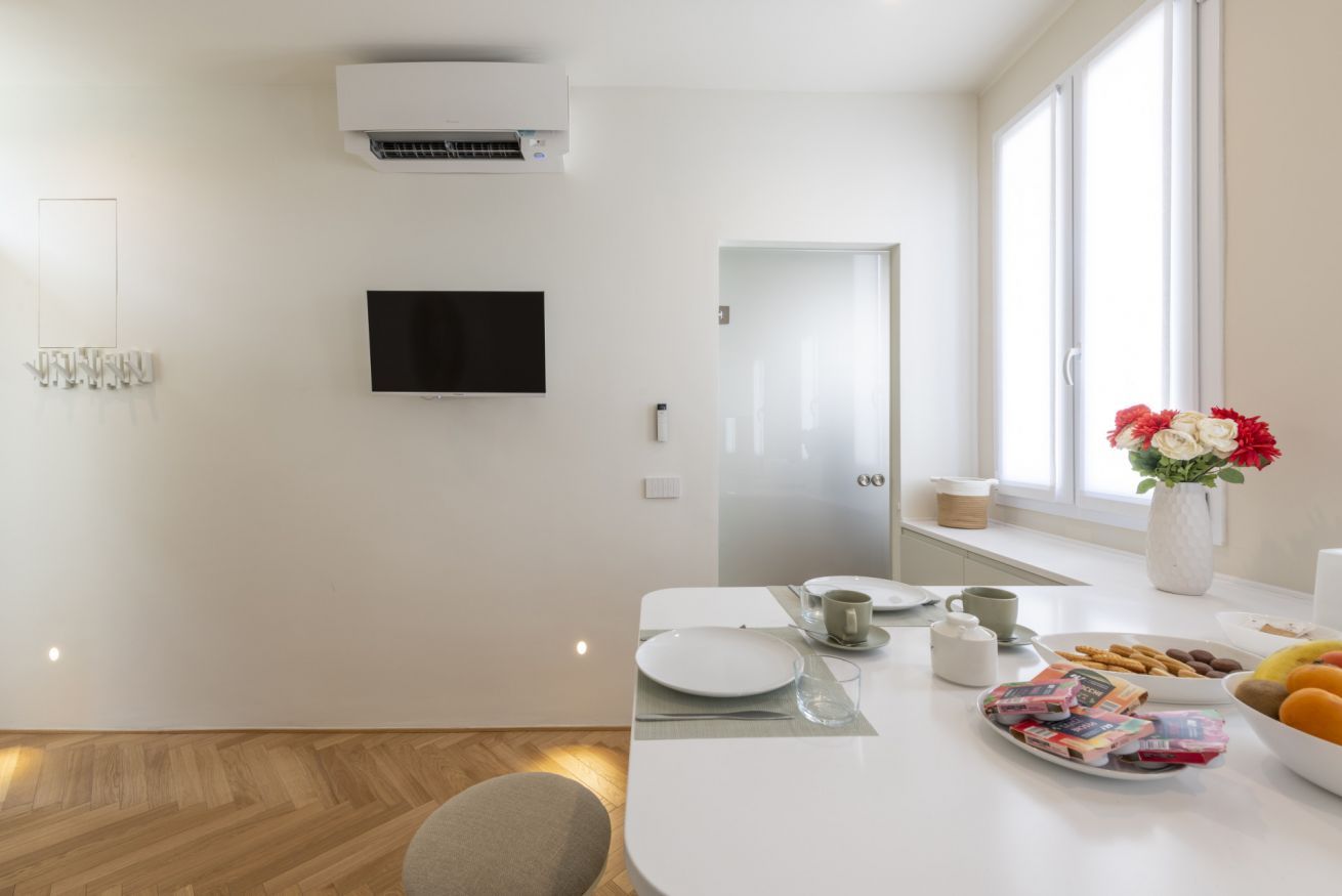 Een moderne keuken met een flatscreen televisie, witte kasten en een raam met uitzicht.