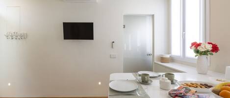 Une cuisine moderne dotée d’un téléviseur à écran plat, de meubles blancs et d’une fenêtre offrant une vue agréable.