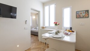 Ett modernt kök med vita bänkskivor, en matplats och en liten köksö med sittplatser.