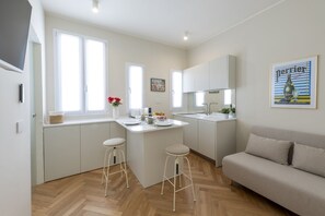A modern kitchen with white cabinetry, a central island with stools, and a large window providing natural light. - Pontaccio, 19 - Your nest in town (Milano)