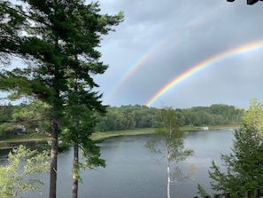 Un lac bordé d’arbres, avec un arc-en-ciel.