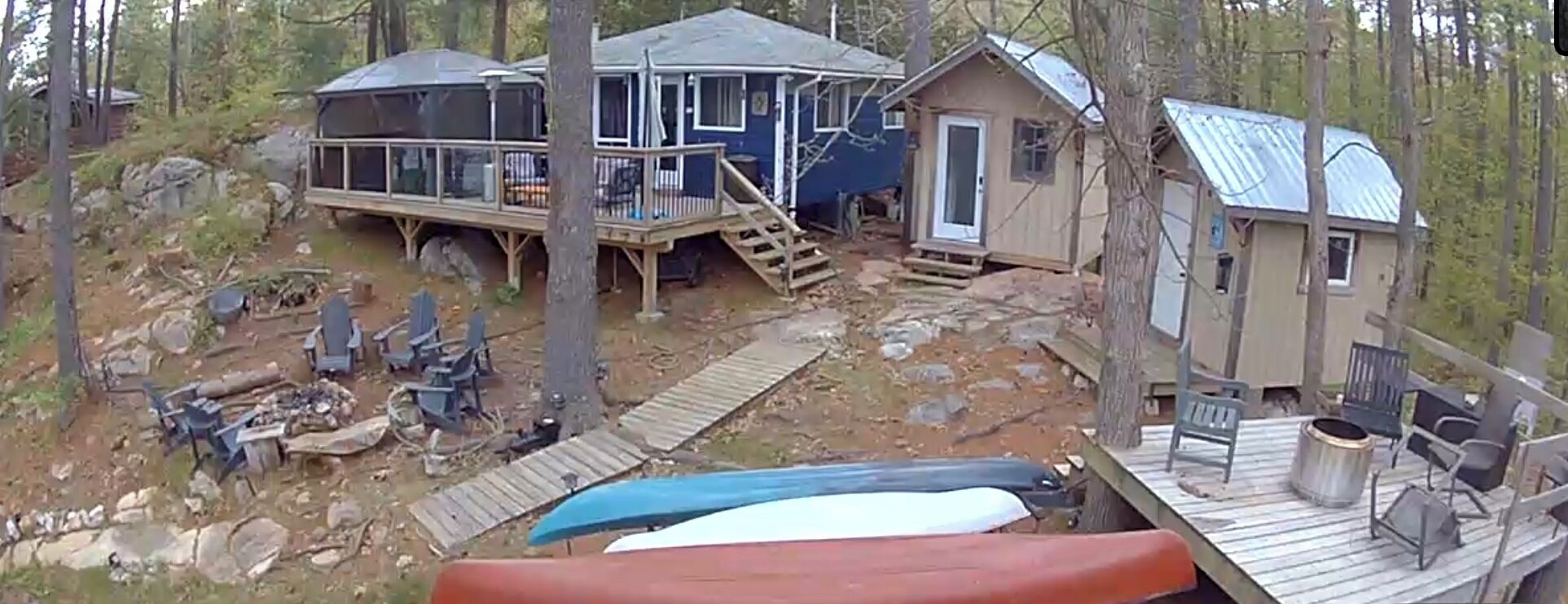 A cabin with a deck, a covered porch, and a small shed.