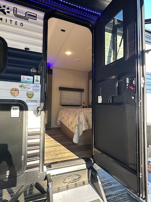 A bus interior with a bed, a window, and a door. - RV Oasis in Charming Downtown Deland (DeLand)