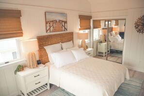 A bedroom with a large bed, a nightstand with a lamp, a dresser, and a mirror. - Private Beach, Water Views, Bike Trail Access, Ready For Your Family! (Eastham)