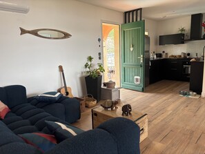 Ein Wohnzimmer mit einer Couch, einer Gitarre, einem spiegelnden Fisch, einer Topfpflanze und einem Holzschrank.