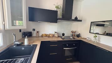 Een moderne keuken met een zwart aanrecht, roestvrijstalen apparatuur en een ingebouwde oven.