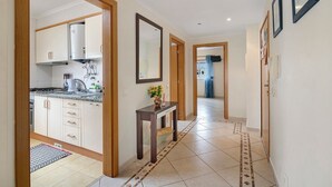 A hallway with a kitchen area, a wooden door frame, a mirror, and a tiled floor. - Apartment 'Algarve House' with Sea View, Wi-Fi and Air Conditioning (Albufeira)