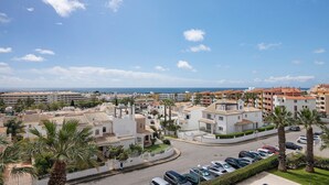 A coastal residential area with buildings, parked cars, and palm trees. - Apartment 'Algarve House' with Sea View, Wi-Fi and Air Conditioning (Albufeira)