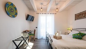 A bedroom with a bed, a desk, a chair, a TV, and a window with curtains. - Casa Addis B&B  (Senigallia)