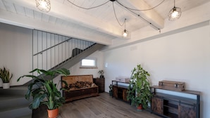 A spacious living area with a staircase, wooden flooring, and various plants. - Casa Addis B&B  (Senigallia)