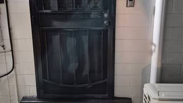 A black door with a mesh screen, a 'WELCOME' mat, and a white air conditioning unit.