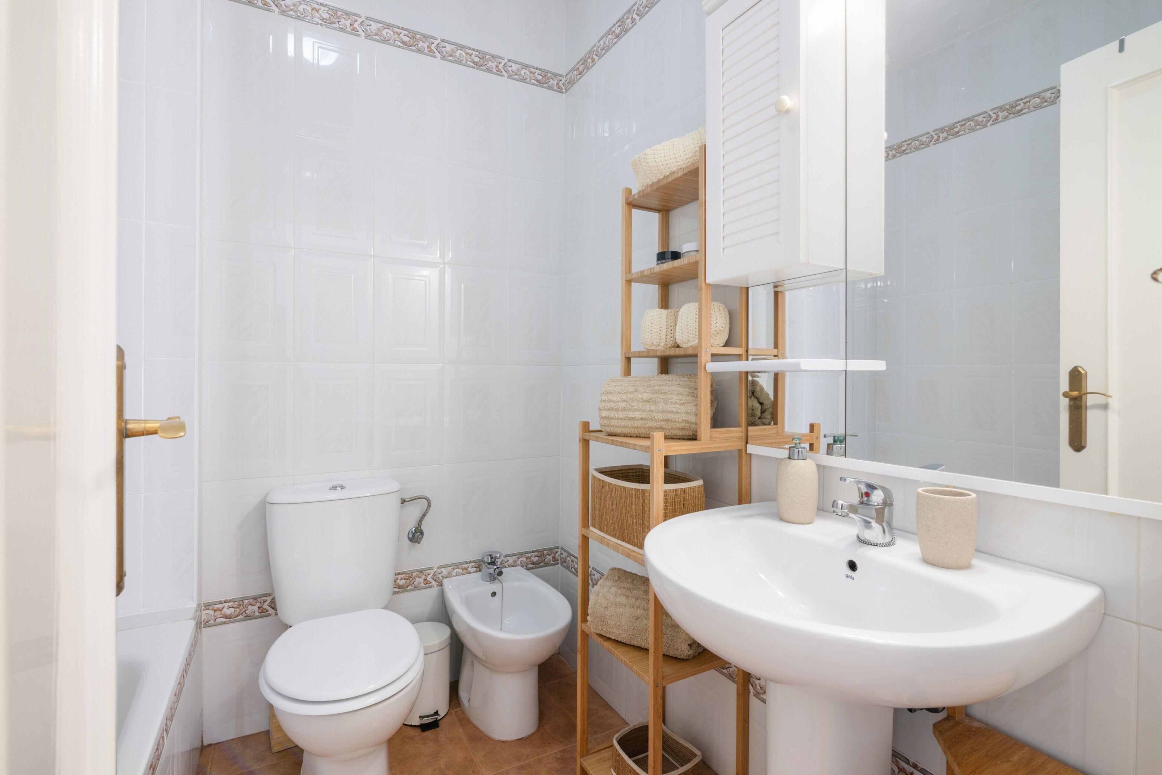 Un baño con inodoro, bidé y lavamanos con espejo.