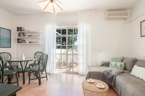 A living room with a dining table, chairs, a sofa, a coffee table, and a bookshelf. - Penthouse in Islantilla with Shared Pool, Wi-Fi, and Air Conditioning (Huelva)