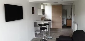 Una cocina moderna con barra, un televisor de pantalla plana en la pared y una puerta de madera que da a otra habitación.