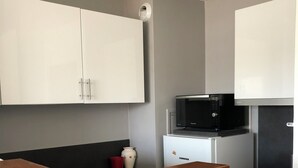 Una cocina moderna con armarios blancos, encimera negra, microondas y refrigerador Liebherr.