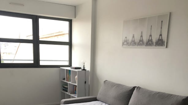 Un dormitorio moderno con una cama, una mesita de noche, una ventana, una estantería y un cuadro colgado en la pared.