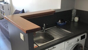 Cocina compacta con lavadora integrada, lavamanos y encimera.