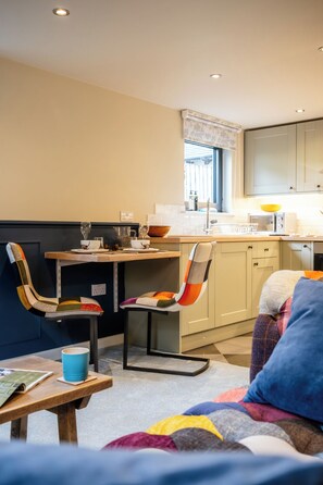 Een compacte woonruimte met een kitchenette, een eethoek en een zithoek met een bank en stoelen.
