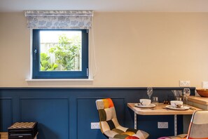 Een eetgedeelte met een raam, een stoel, een tafel gedekt met borden en glazen, en een schaakbord.