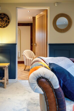 Een slaapkamer met een bed, een stoel, een houten deur en een spiegel aan de muur.