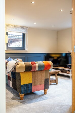 Een gezellige woonkamer met een kleurrijke bank, een televisie en een raam met uitzicht.