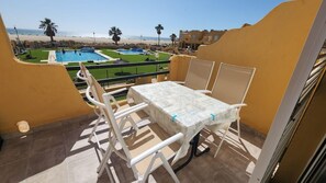 A balcony with a table and chairs, overlooking a pool and beach. - 142 - Livingtarifa Mango (Tarifa)