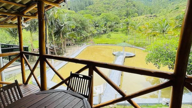 A wooden deck with a table and chairs overlooking a river and lush greenery.