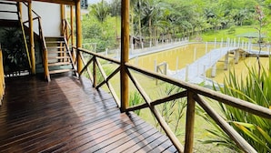 A wooden deck with a view of a lush green landscape and a pond.
