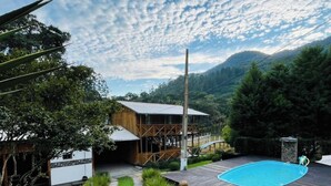 A modern house with a wooden deck, a swimming pool, and a well-maintained garden.