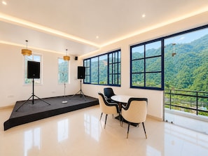 Una habitación moderna con un escenario, dos altavoces y una mesa con sillas.