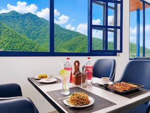 Un comedor con vistas a la montaña, una mesa servida con platos de comida, bebidas y cubiertos.