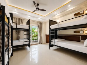 A hotel room with bunk beds, a ceiling fan, and a view of greenery outside. - Hotel Weekend Heights (Rishikesh)