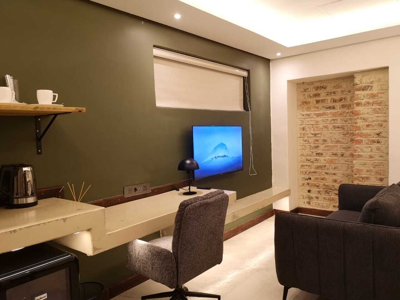 Une chambre moderne équipée d’un téléviseur à écran plat, d’un bureau, d’une chaise et d’un canapé.