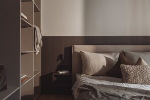 Una camera da letto con un letto, cuscini, un comodino, una libreria e un armadio.