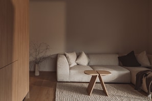 Un soggiorno moderno con un divano, un tavolino in legno e un vaso decorativo con rami.