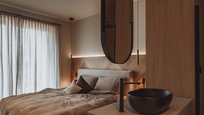 A modern hotel room with a bed, bedside table, and a large mirror. - DAS AICH - Suite Luma (Aich-Assach)