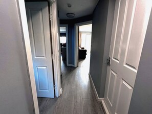 Un pasillo con una puerta que da a una habitación, otra puerta más adelante y una tercera al final.